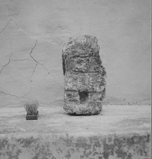 Sculptured stone, human figure seated on heels.