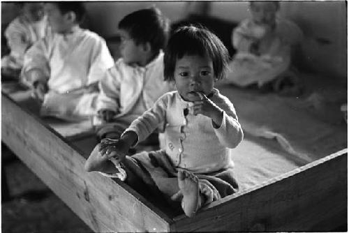 Baby with a finger in her mouth and touching one foot