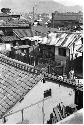 View of the roof tops of a village with smokestacks in the distance