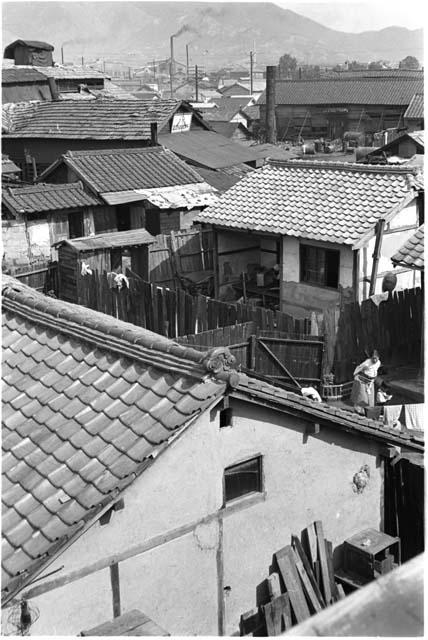 View of the roof tops of a village with smokestacks in the distance