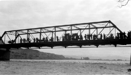 Group of people standing on a bridge, distant mountains