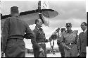 Military personnel standing beside plane