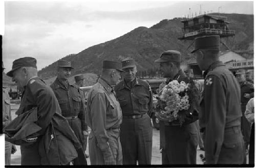 Military personnel talking, one man holding flowers