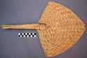 Fan, woven palm leaf, curved triangular blade, braided handle, notched