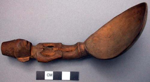 Wooden spoon, handle carved in human effigy, hands resting on flexed knees, turb