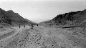 People walking in desert between mountains