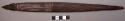 Spear head of dark wood with incised designs on upper part of 1 side
