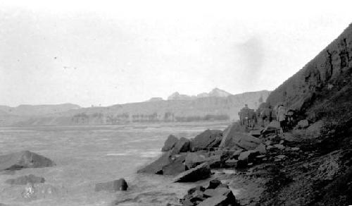 People climbing along rocks by river