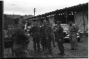 Group of military personnel standing on a dirt road