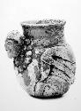 Jar with hollow human head in relief.  Disintegrated plumbate wear.
