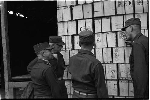 Military personnel discussing a stack of boxes