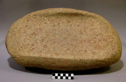 Metate, ground stone, ridges at either side at top, triangular in cross-section