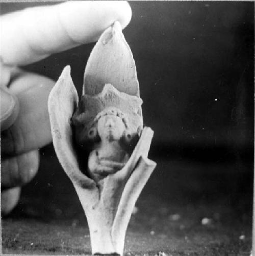 Ceramic figurine, human with crossed arms in sheath of leaves