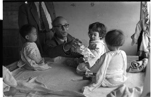 Man playing with three babies