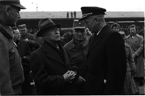 Man in hat talking to man in uniform in a crowd