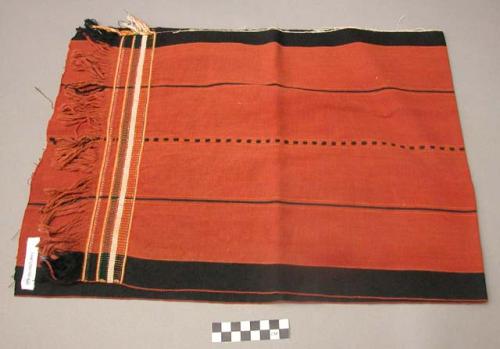 Textile; black and red striped, fringed.