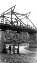 People looking up at bridge spanning small river