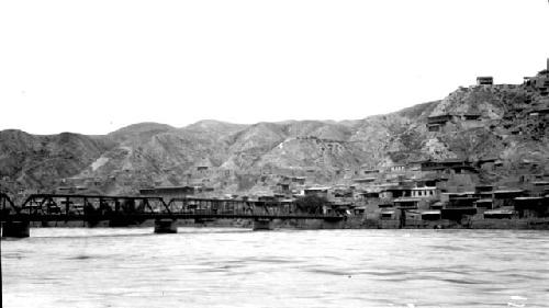 Bridge spanning wide river, town on hilly bank