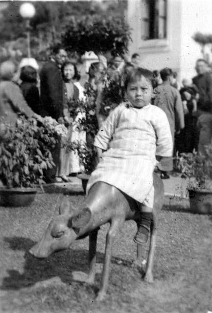 Child sitting on deer statue