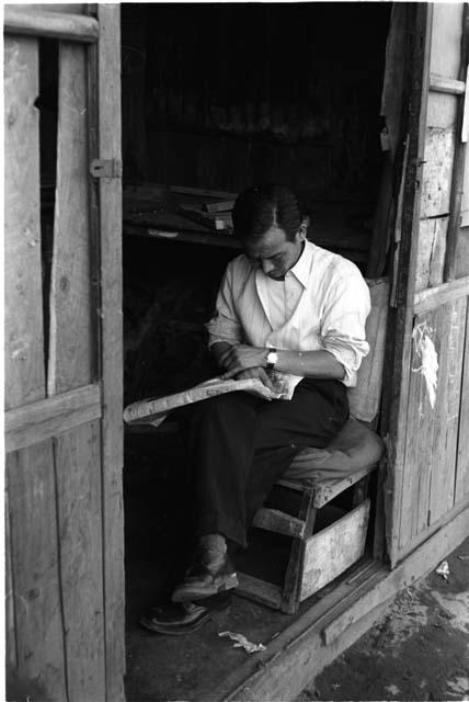 Man sitting and reading, with legs crossed