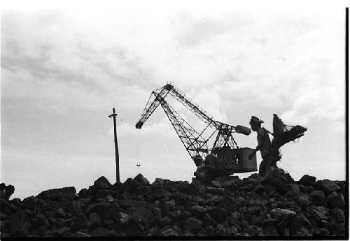 Cranelike construction machine lifting an object and worker walking