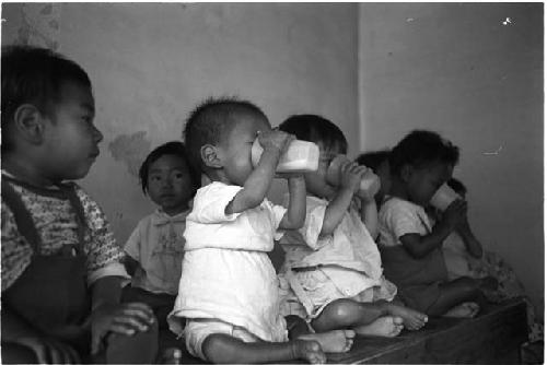 Two babies drinking from cups