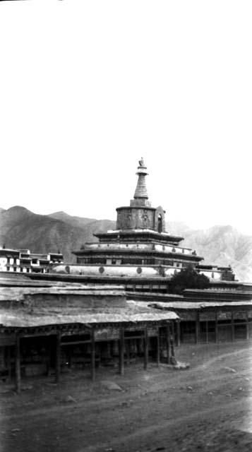 Stupa with outbuildings, road and mountains