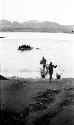 Two men carrying water in buckets on poles to shore, boat on river with people