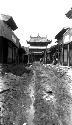 Muddy road to gateway, man carrying bundles