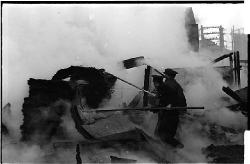 Workers going through the wreckage of a burned down building