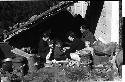 Family sitting under a makeshift shelter