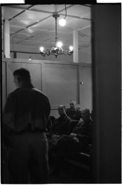 Men sitting down and a chandelier hanging from the ceiling