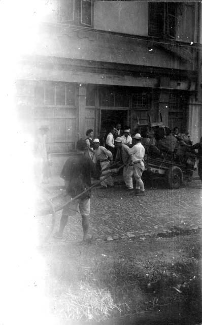 Men pulling carts on street