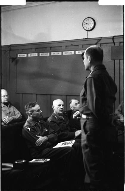 Man in uniform speaking to a group sitting down