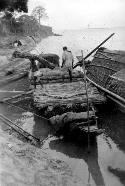 Men carrying bundles of wood from boat