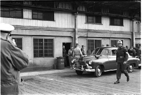 Men leaving a building and walking towards a car