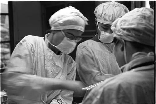 Three people performing surgery