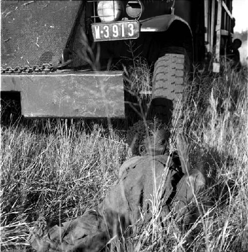 /Naoka sitting in front of an expedition truck, wrapped in her kaross