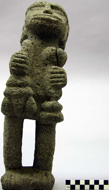 Standing large lipped granite figure with head tilted back grasping objects