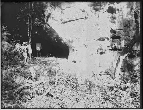 Men near Sculpture in Cave Opening