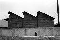 Woman running in front of building with three slanted roofs.