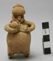 Figurine rattle of woman nursing child with another on her back