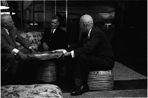 Three men sitting around a table in a lounge