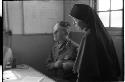 Man sitting down and a nun standing next to him