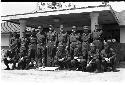 Group of men in uniform posing for picture in front of a building