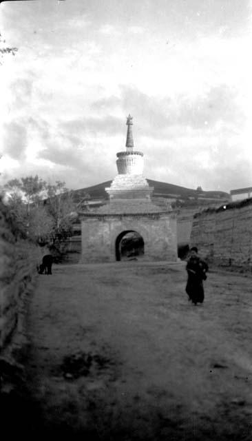 Stupa with archway, monk walking in front