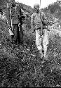 Two chinese men standing on hillside holding rifles