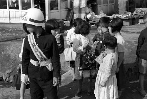 Children on street. One boy is dressed as safety police officer.