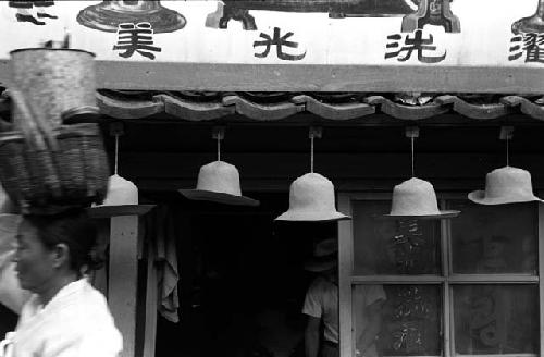 Hats hanging in a row from awning of store.