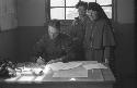 Man at a desk and a nun standing behind him